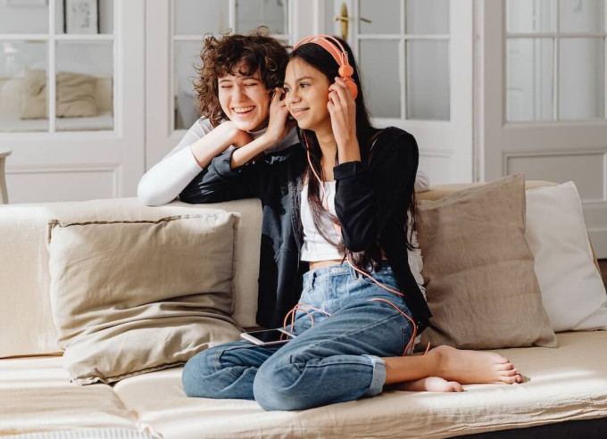 Two young women sharing headphones to listen to a podcast