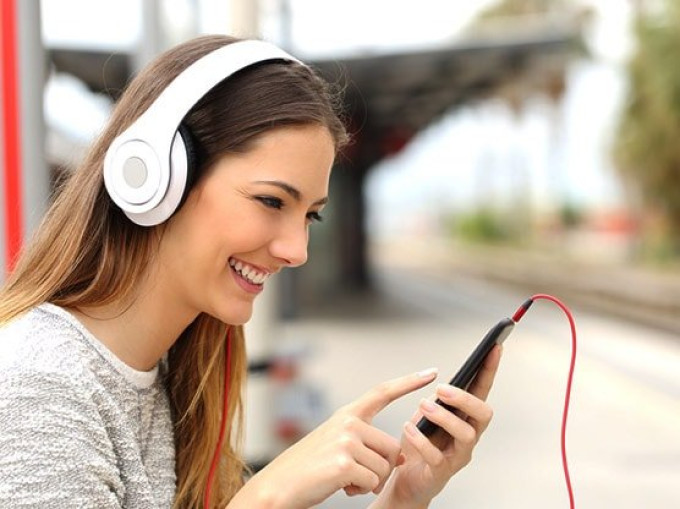 Young woman wearing headphones connected to a mobile phone