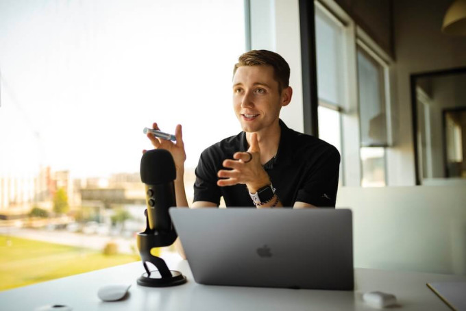 Male podcast host answering customer FAQs - view of city in the background