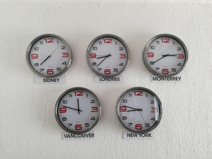 Five clocks on a wall depicting time zones around the world