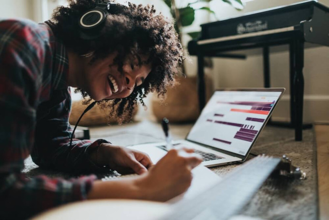 Happy woman wearing headphones while writing