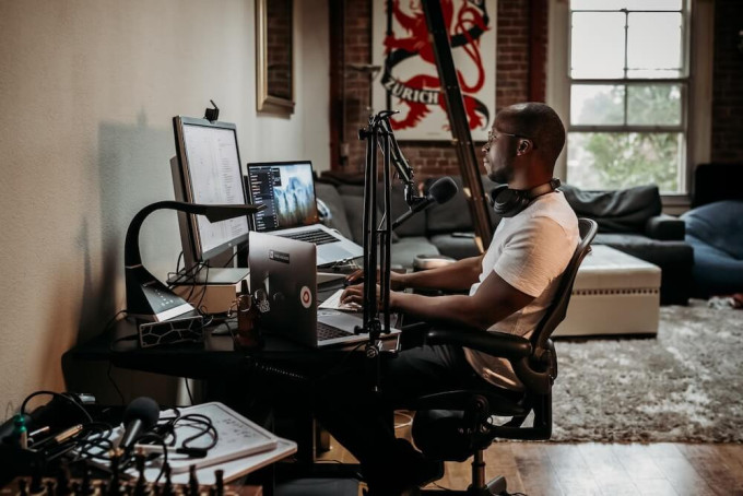 Man sitting at desk with laptop and podcast equipment