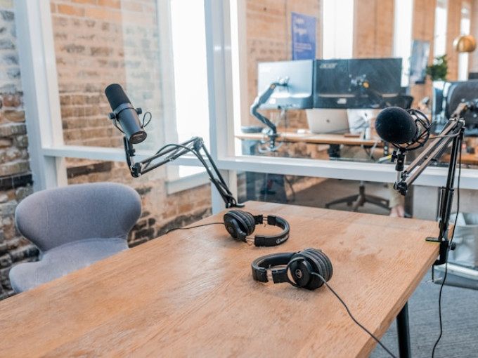 Microphone and headphones on a desk in an office, recording a podcast for a podcast network