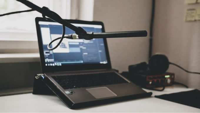 Image of podcast studio with microphone, laptop and headphones