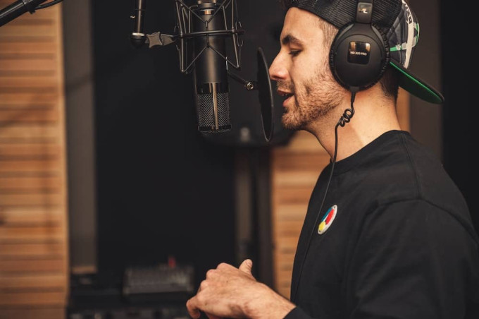 Man wearing headphones using a a microphone with pop filter attached