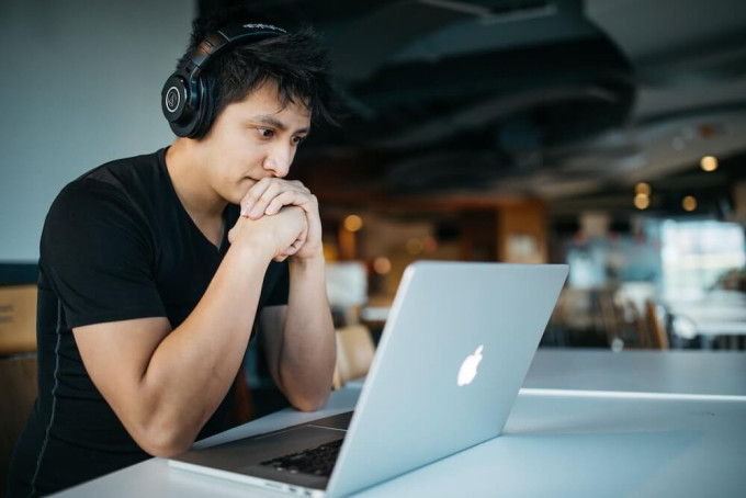 Young man wearing headphones sitting in front of laptop