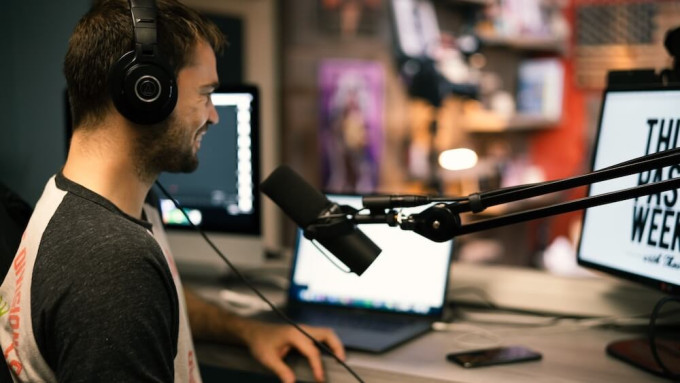 Podcast host sitting in from of microphone looking at computer screen