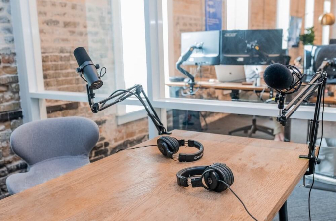 Desk with podcast microphones and headphones on it
