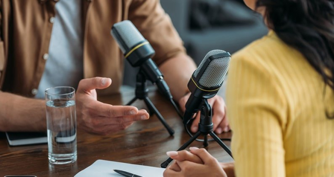 Close up of a man and woman doing a podcast interview