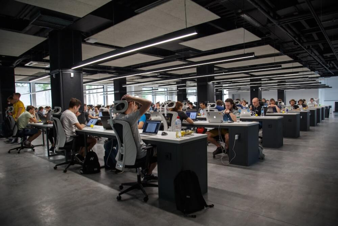Large open plan office filled with employees working on their laptops