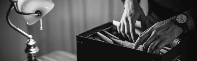 Closeup of hands going through paper files, considering blog vs. podcasts